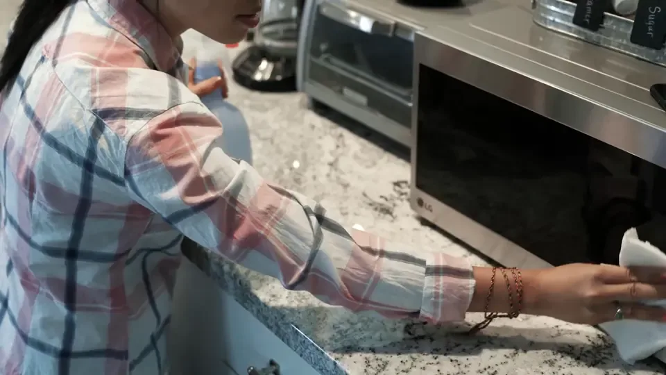 A cleaner wiping a microwave